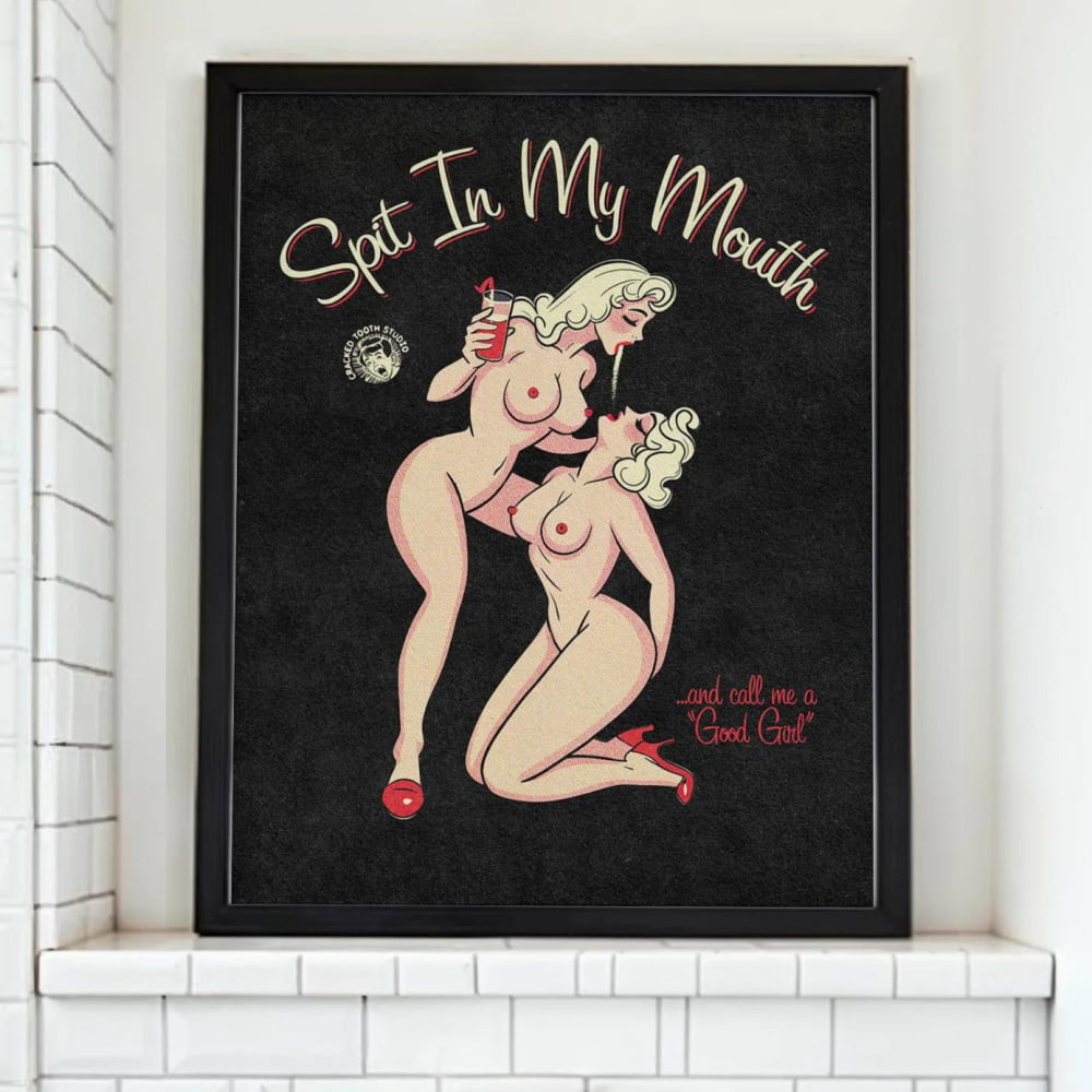 a bathroom with a framed poster of two naked women on the wall above a white toilet.