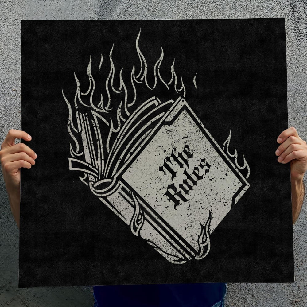 A person is holding up a black poster with a white graphic design depicting a book with flames on the cover.