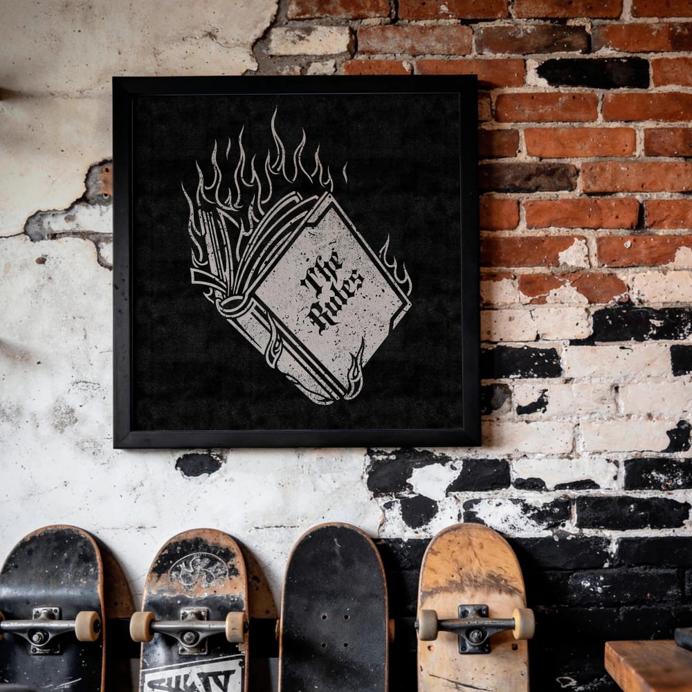 a wall with a framed artwork depicting a book with flames, and several skateboards leaning against the wall.