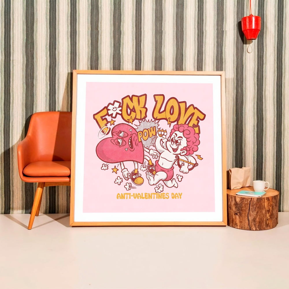 a framed poster with a pink background and a cartoon illustration of a character with a pink heart. The poster has the text "F*ck Love" and "ANTI-VALENTINE'S DAY" written on it.