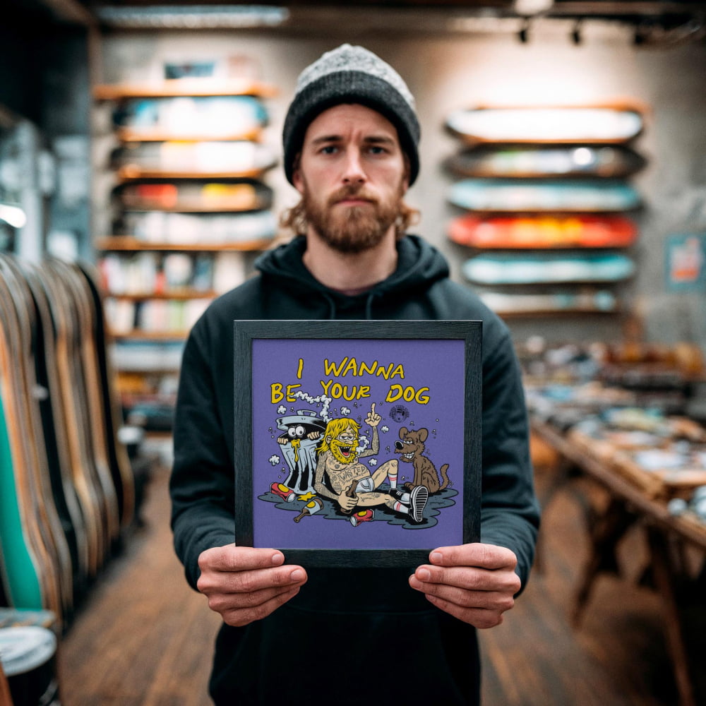 A man holding a framed picture with a cartoon-style illustration of a dog and a person, along with the text "I WANNA BE YOUR DOG".