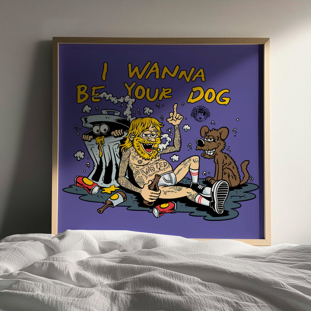 The image is a framed poster with a cartoon-style illustration of a man and a dog. The man is sitting on the floor, holding a beer bottle, while the dog is sitting next to him. The text on the poster reads "I WANNA BE YOUR DOG".