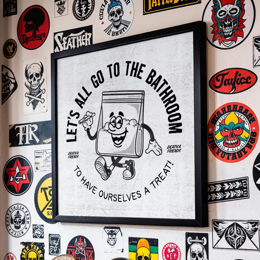 a wall adorned with a variety of stickers, patches, and graffiti, including a central sticker with a cartoon character and the text "Let's all go to the bathroom to have ourselves a treat!"