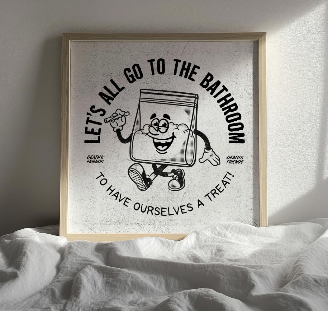 A framed poster with a cartoon character and text, placed on a bed with white sheets.
