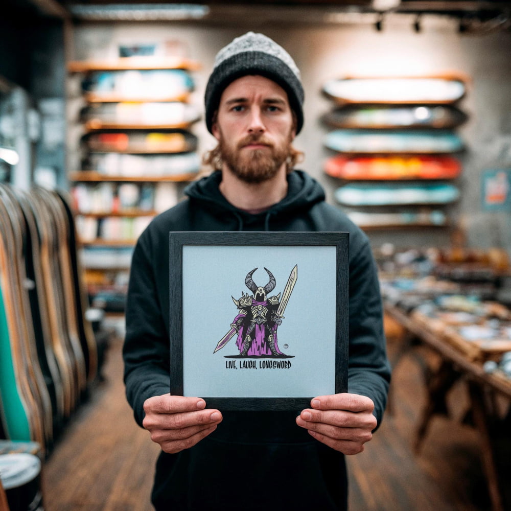 A man holding a framed artwork with a dragon illustration on it, standing in a shop with shelves of skateboards in the background.