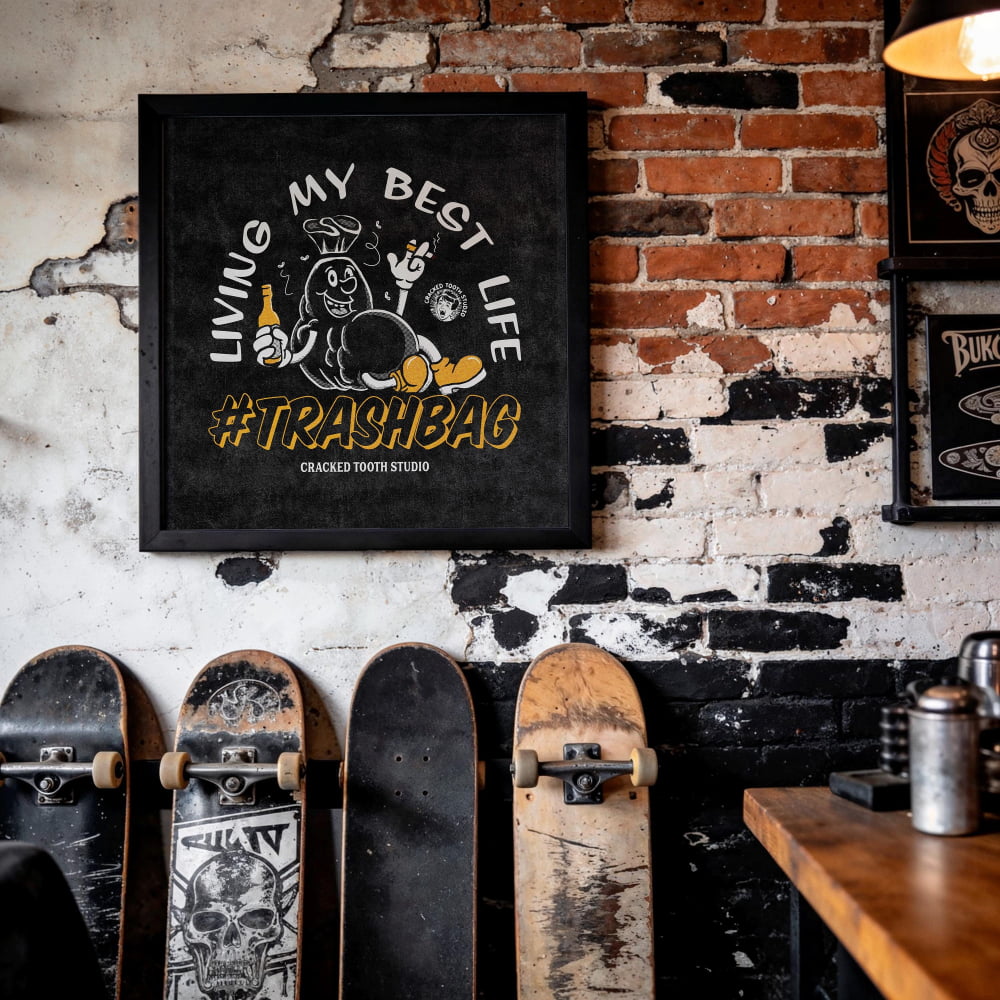 a wall with a framed poster that says "Living My Best Life #TRASHBAG" and a brick wall with a skull and crossbones design. There are several skateboards leaning against the wall, including a black skateboard with a skull and crossbones design.