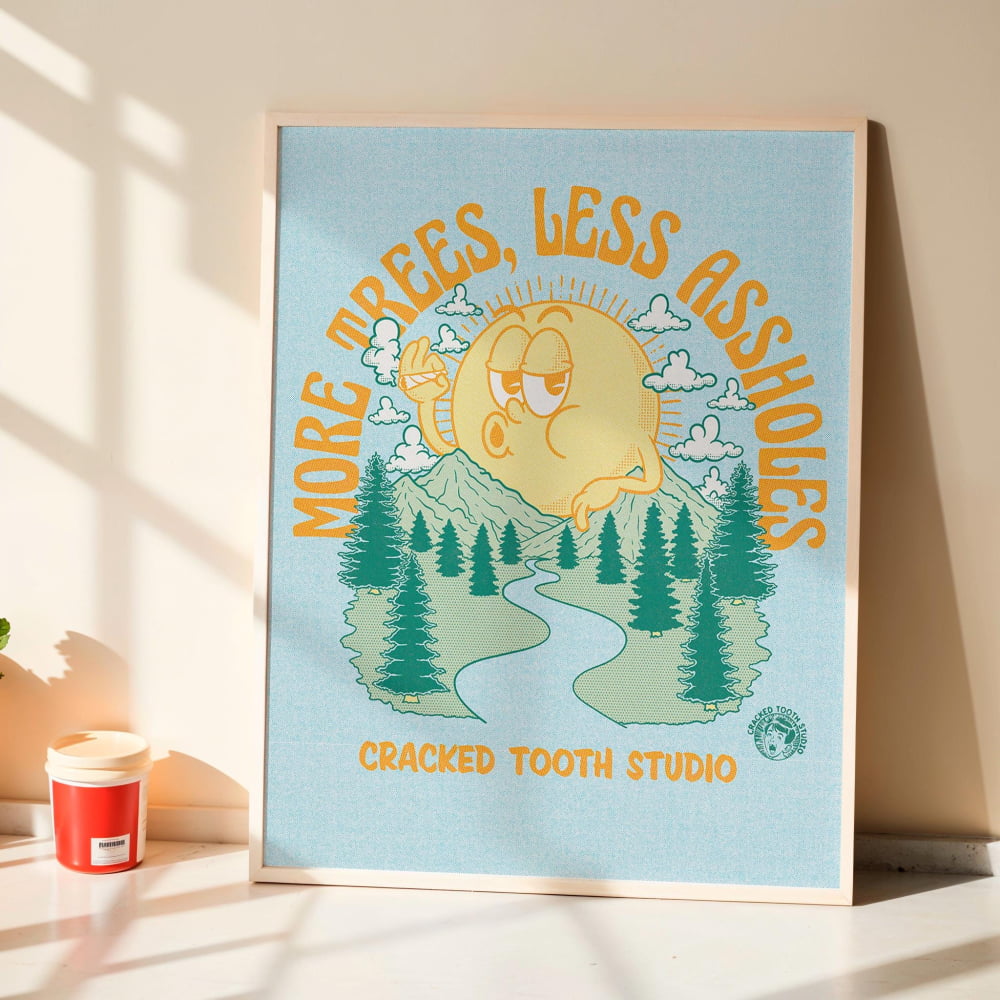 a poster with a cartoon sun and trees, along with the text "More trees, less ashholes" and "Cracked Tooth Studio".