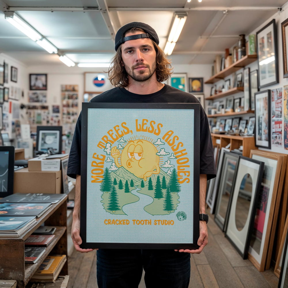 A man holding a framed poster with a cartoon character and text in a room filled with various items.