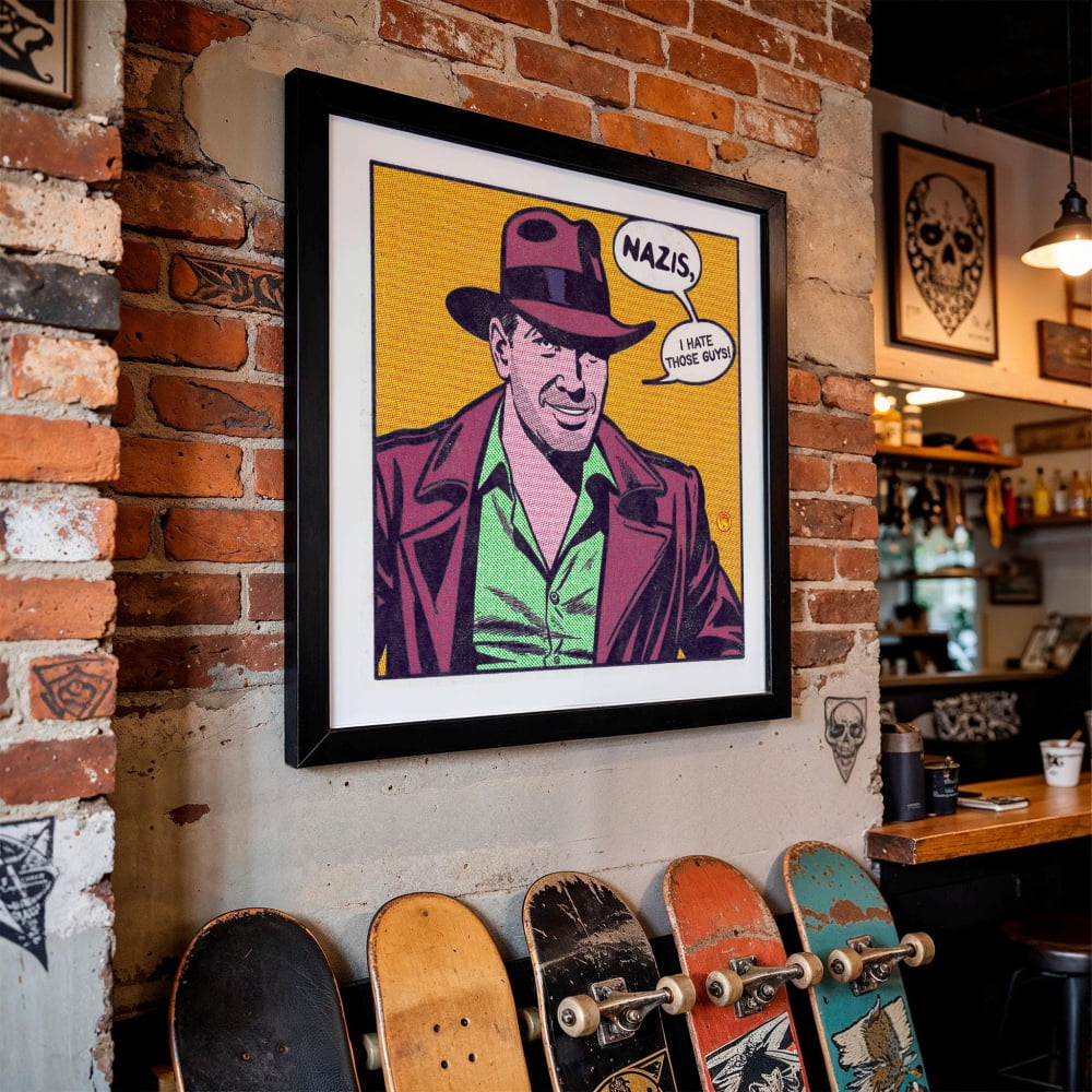a framed pop art-style portrait of a man wearing a fedora and a suit, with the word "NAZIS" written above him. The portrait is displayed on a brick wall, and there are several skateboards leaning against the wall in the foreground.
