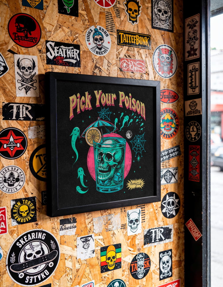 a wall covered in various stickers, posters, and graffiti, with a framed poster hanging prominently in the center.