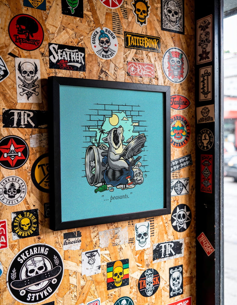 a wall covered in various stickers, patches, and graffiti, including a framed illustration of a bird.