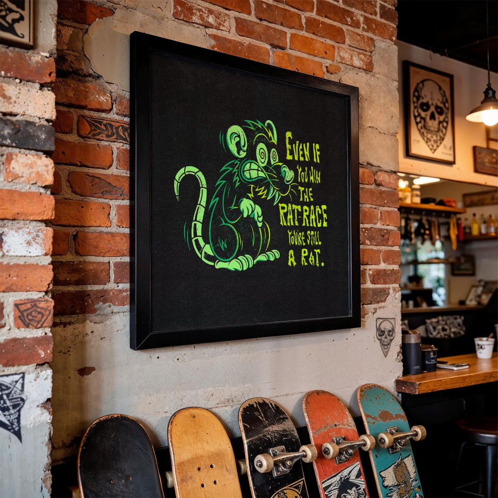 a framed poster of a rat with a humorous caption, hanging on a brick wall. Below the poster, there are several skateboards lined up, suggesting a skateboard shop or a skate park.