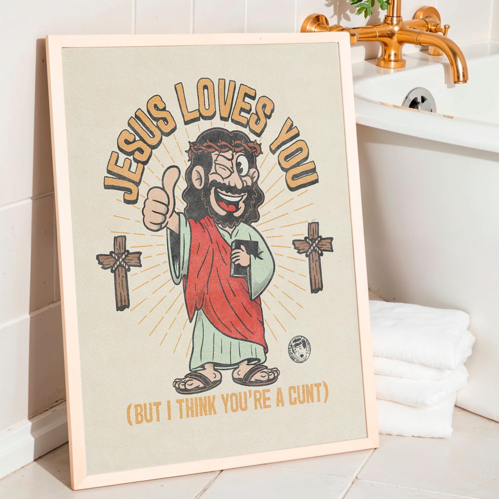 A framed poster with a cartoon image of Jesus wearing a red robe and holding a cup, with the text "JESUS LOVES YOU" and "(BUT I THINK YOU'RE A CUT)" below.