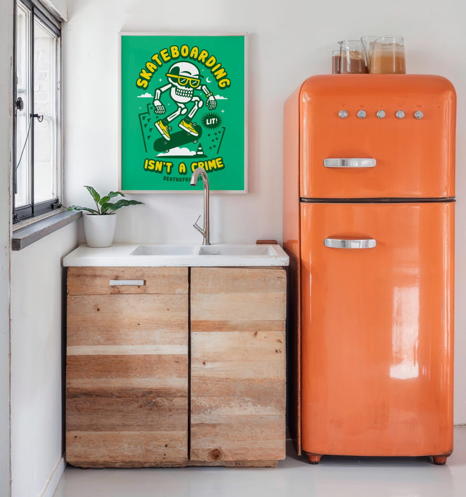 a kitchen with a vintage orange refrigerator, a sink, and a framed poster on the wall that says "Skateboarding isn't a crime".
