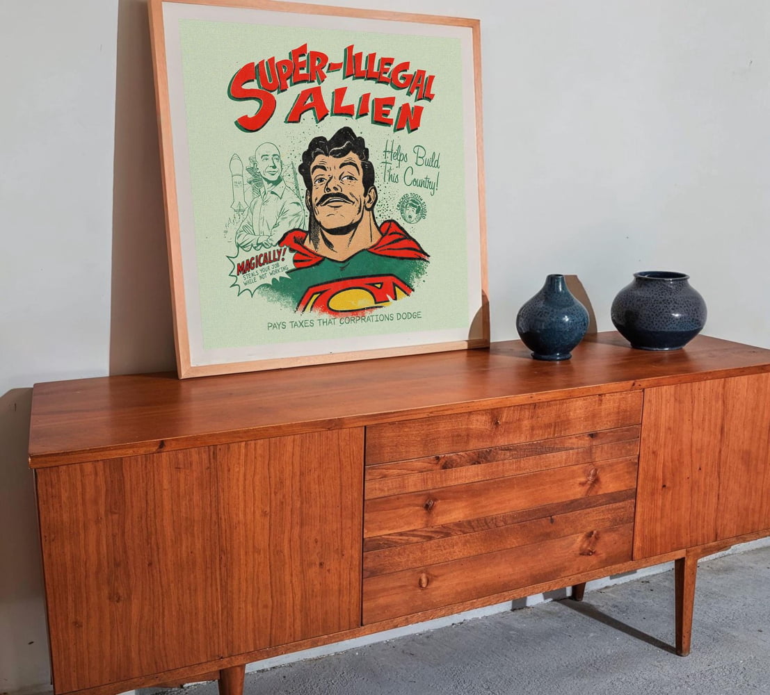 a framed poster of a comic book character, specifically Superman, displayed on a wooden cabinet or dresser.