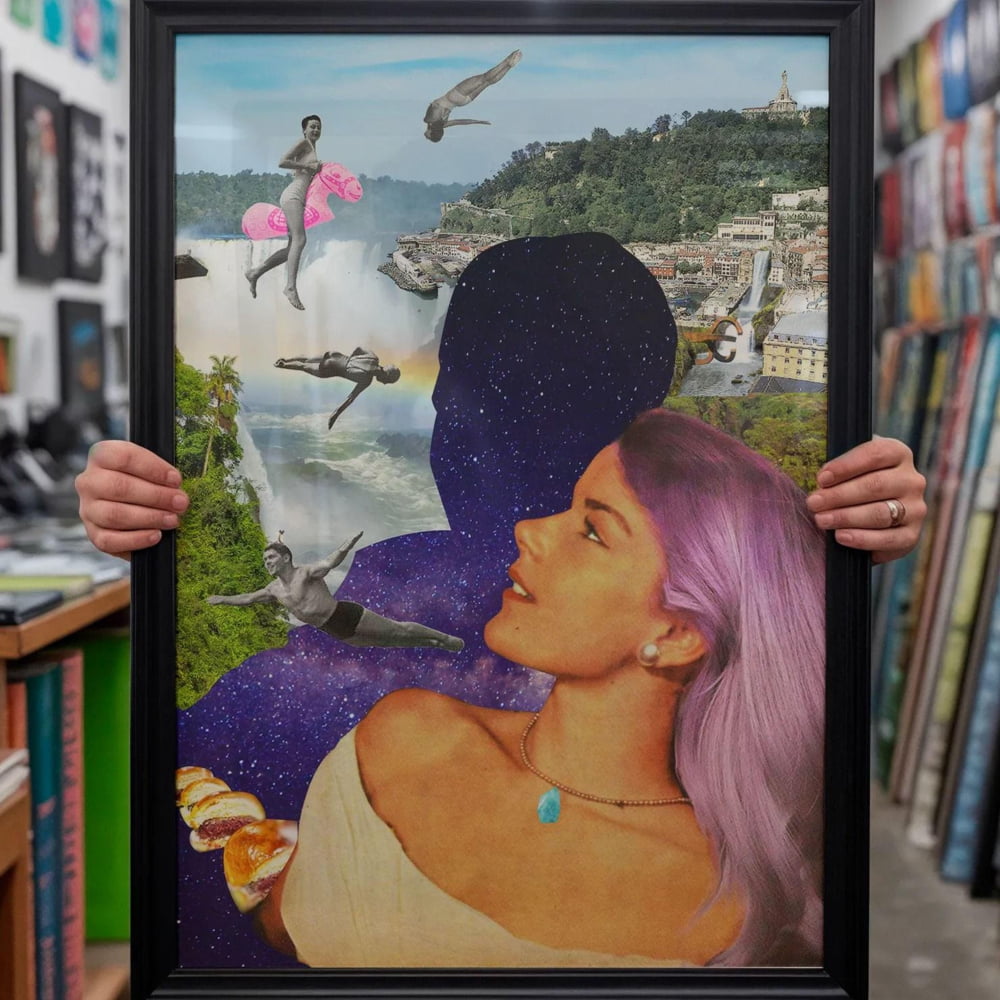 A person is holding up a framed collage of various images, including a woman with purple hair, a cityscape, and flying objects.