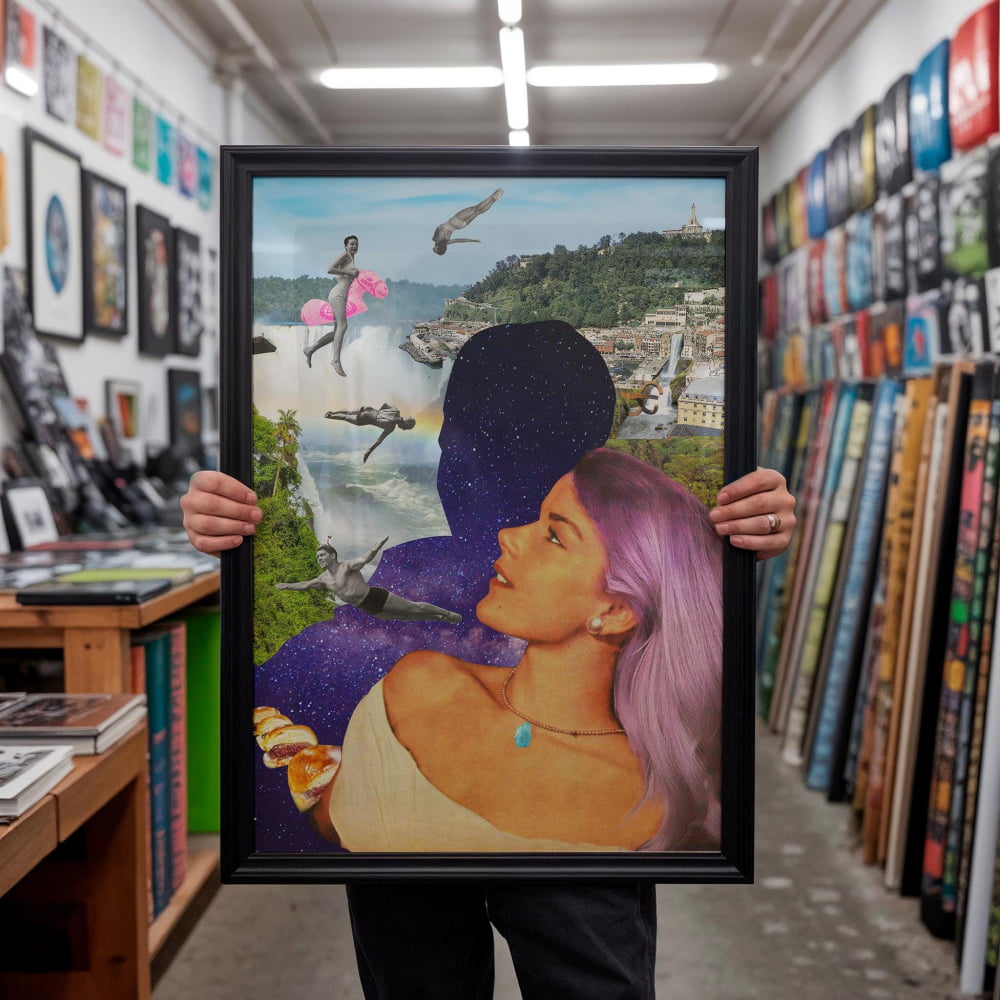 A person is holding up a framed collage of various images, including a woman with purple hair, a cityscape, and flying objects.