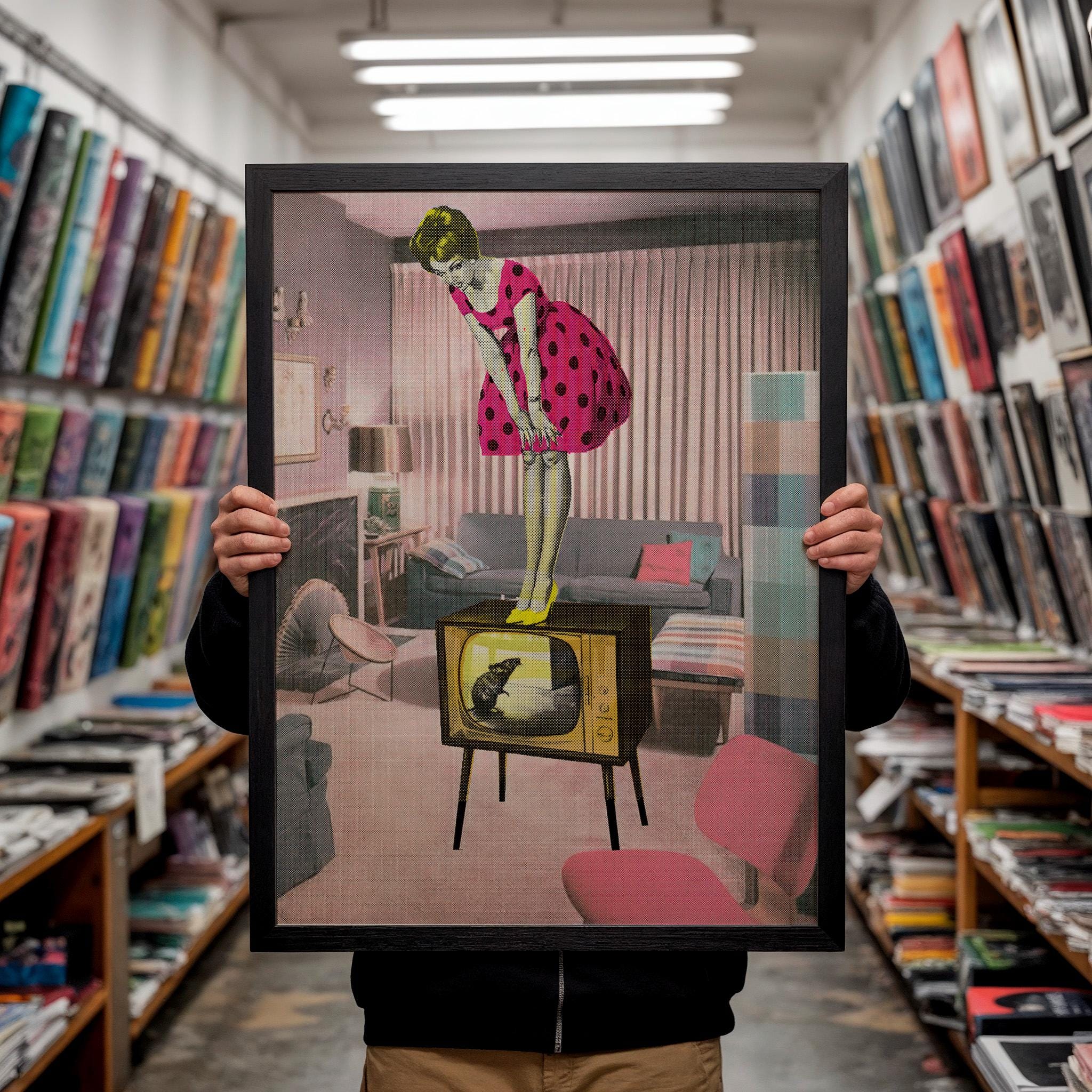 A person is holding up a framed image of a woman in a pink polka dot dress standing on a television set in a living room.