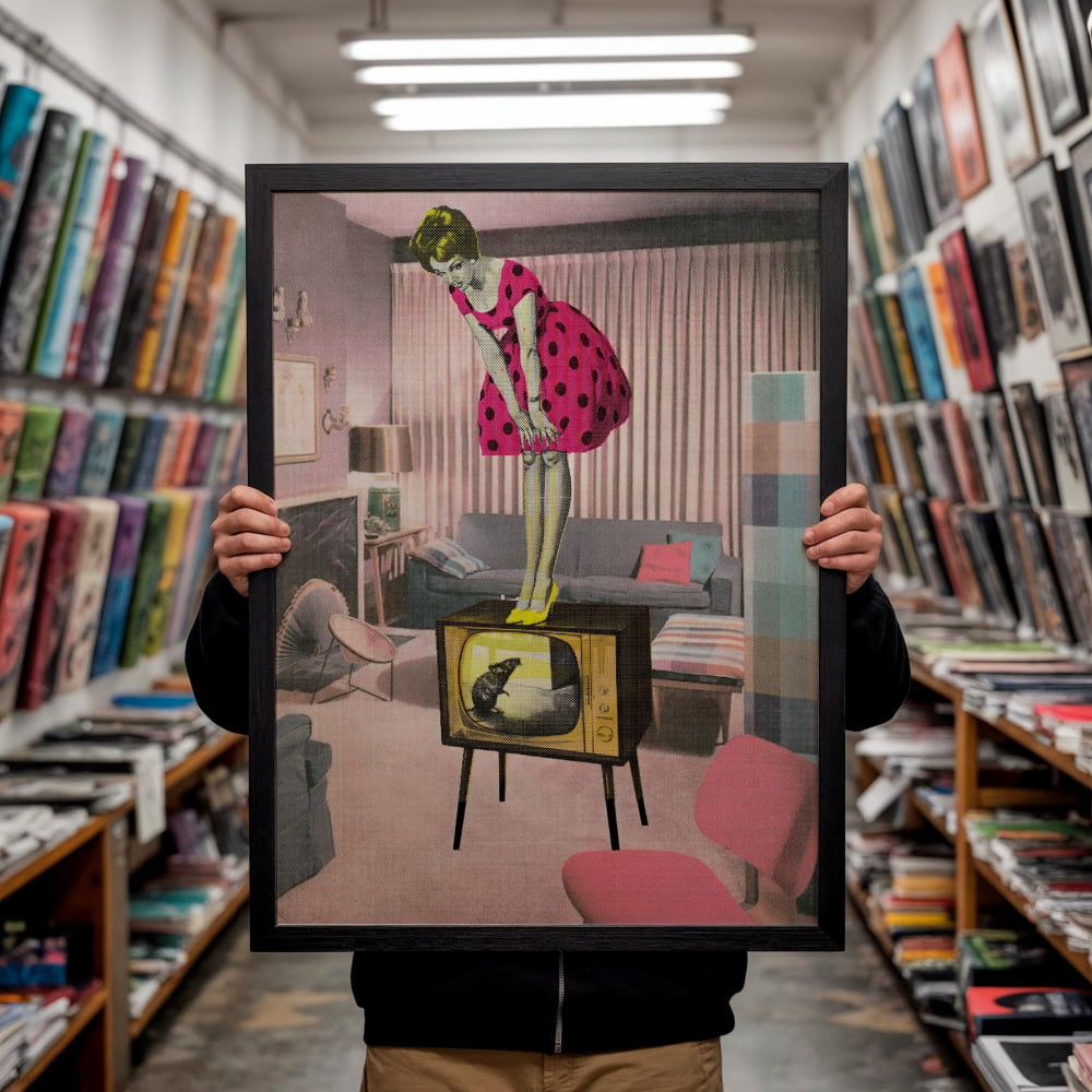 A person is holding up a framed image of a woman in a pink polka dot dress standing on a television set in a living room.