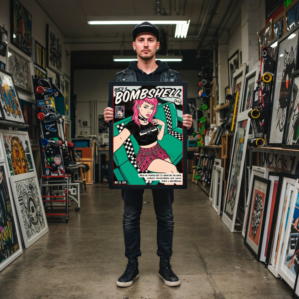 A man is standing in a room filled with various artworks, holding a framed poster of a pop art style illustration.